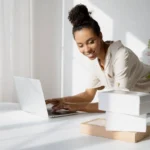 Pelaku bisnis online mengemas pesanan sambil bekerja di laptop dari rumah